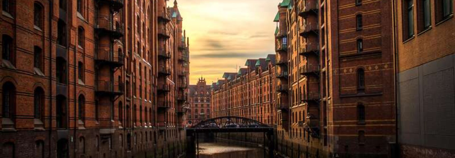 Historické sklady z červených tehál lemujú pokojný kanál pri západe slnka v hamburskej štvrti Speicherstadt.