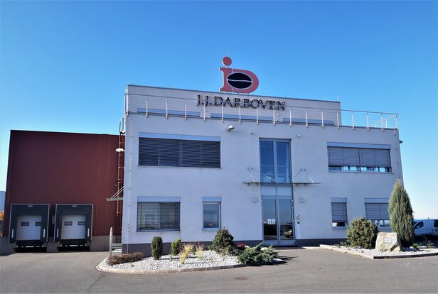Moderní budova společnosti J.J. Darboven s průzračně modrou oblohou a upraveným vchodem, ideální pro distribuci kávy.