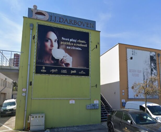 Exteriérový pohľad na budovu J.J. Darboven s reklamou na kávu a nástennou maľbou "Navrhnite si svoju budúcnosť".