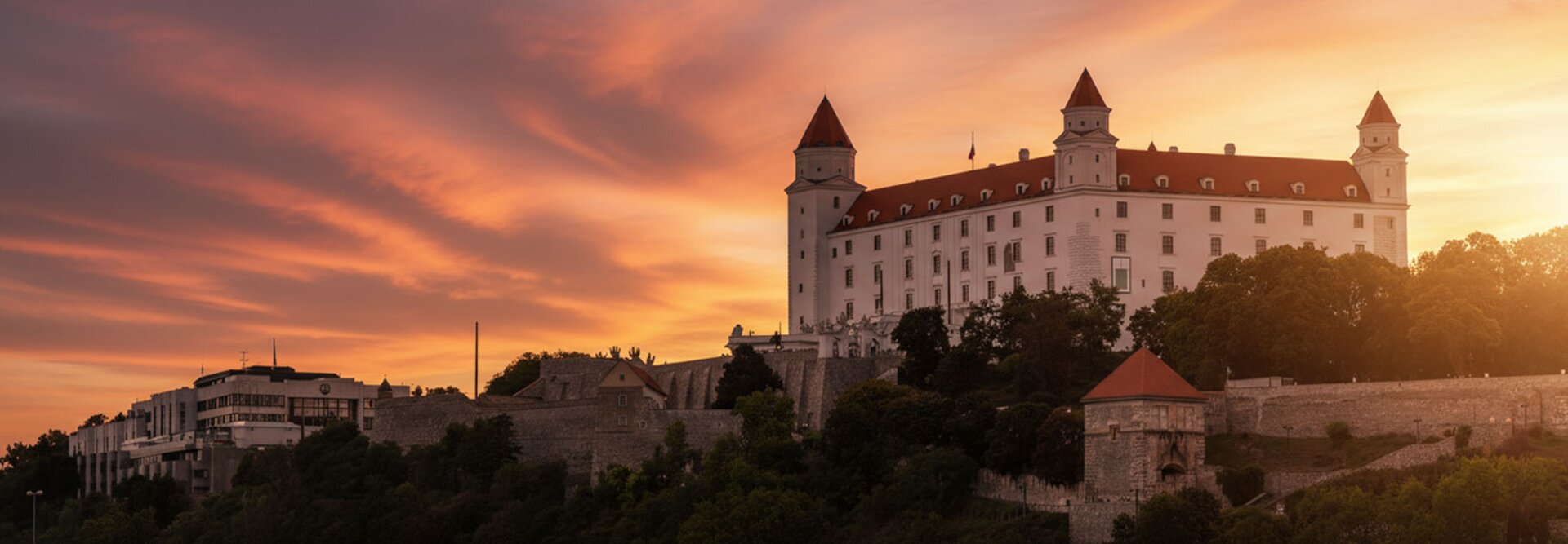Bratislavský hrad osvetlený nádherným západom slnka, ktorý ukazuje jeho historickú architektúru na pozadí žiarivej oblohy.