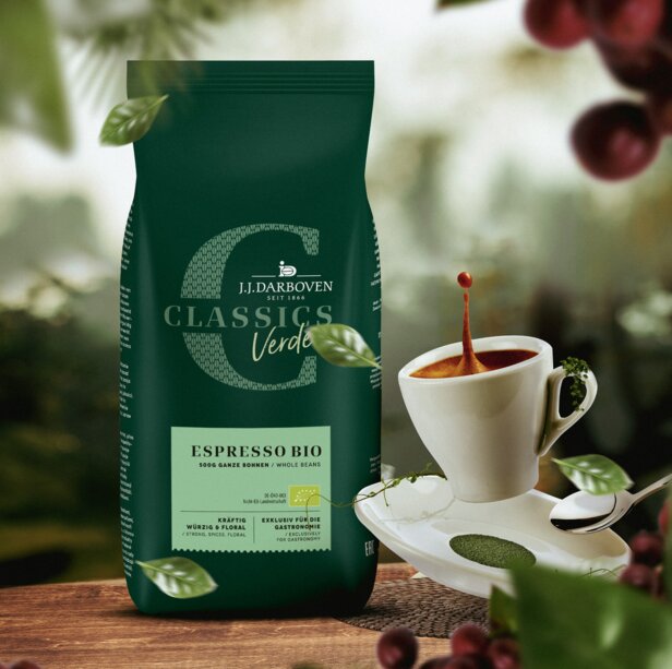 Bio espresso J.J. Darboven s bohatým šálkem a zeleným obalem uprostřed kávových rostlin a zrn.
