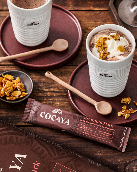 Lahodná horká čokoláda Cocaya Premium Dark podávaná s křupavými polevami, ideální pro příjemné posezení.