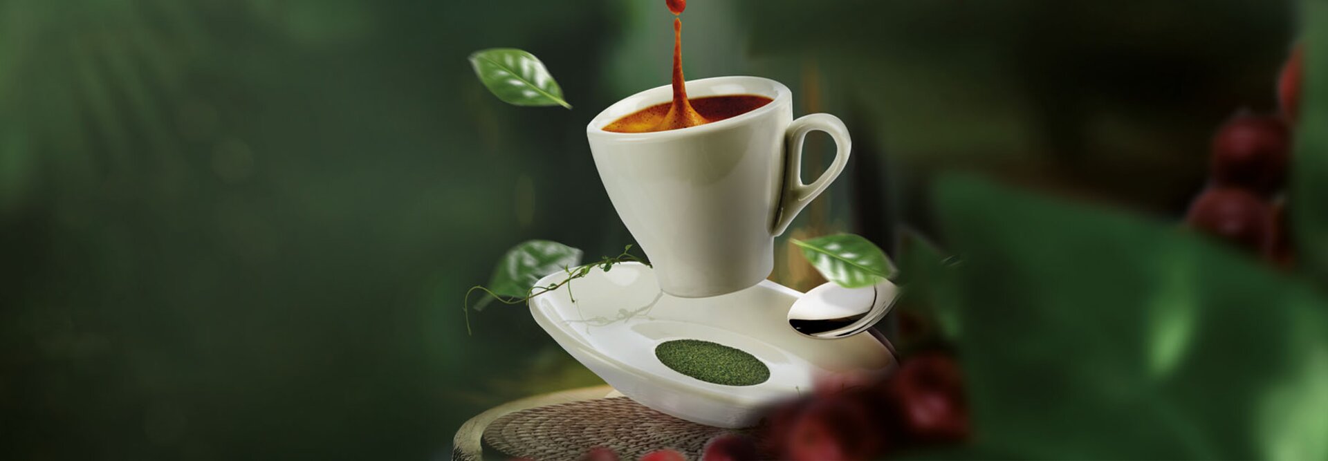 Šálek kávy s párou a zelenými listy vedle něj na svěžím přírodním pozadí.