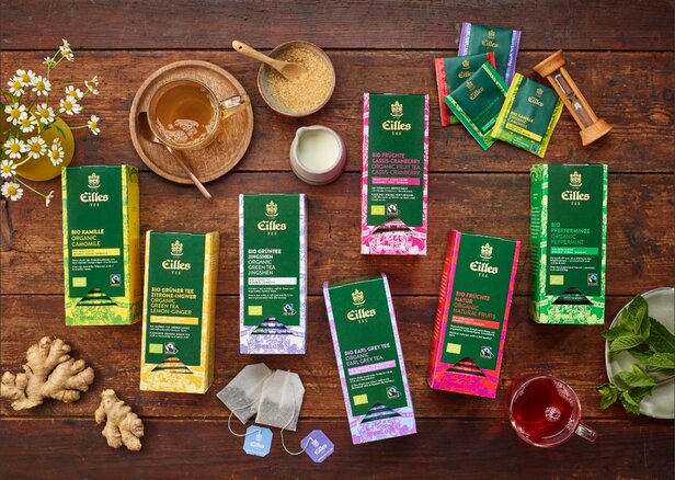 Een assortiment biologische thee van Eilles, waaronder kamille, groene thee en fruitmelanges, op een rustieke houten tafel.