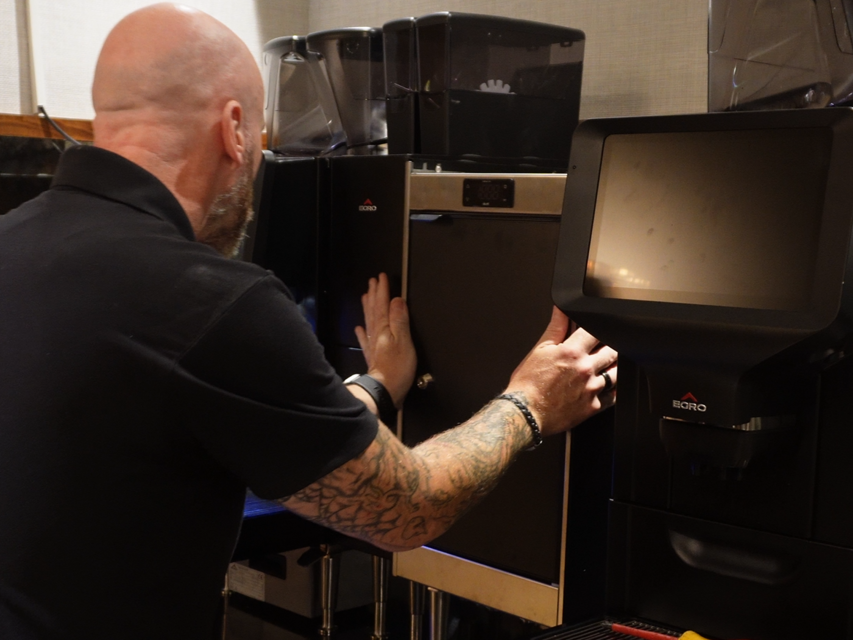 A barista operates a modern coffee machine in a cafe, adjusting settings for efficient beverage preparation.