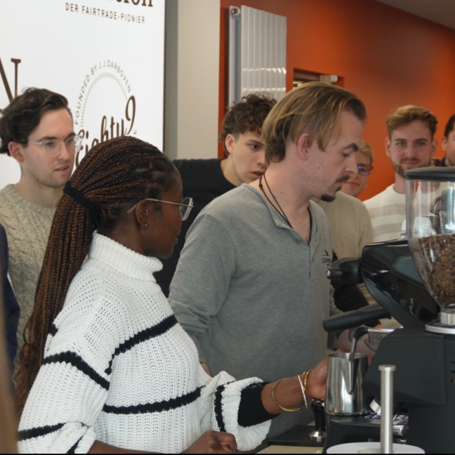 Group of baristas learning coffee preparation techniques in a vibrant café setting during a training session.