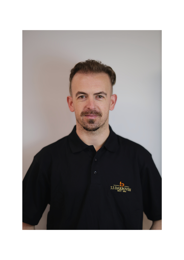 Professional headshot of a man in a black polo shirt featuring the J.J. Darboven logo, against a plain background.