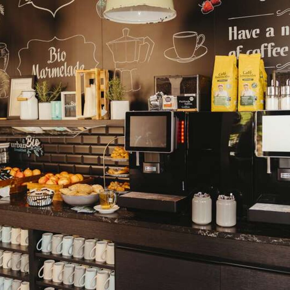 Modern coffee station with self-service machines, fresh pastries, and a variety of teas in a cosy café setting.