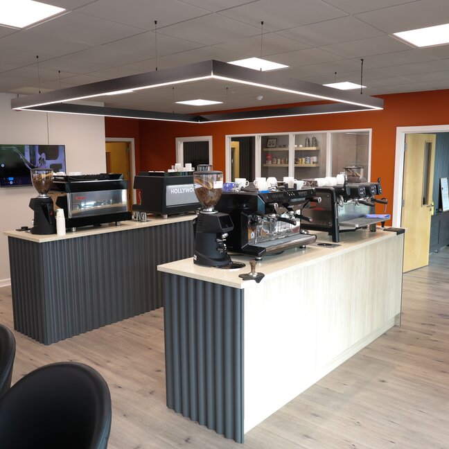 Modern coffee shop interior featuring sleek espresso machines and a welcoming atmosphere with orange accents.