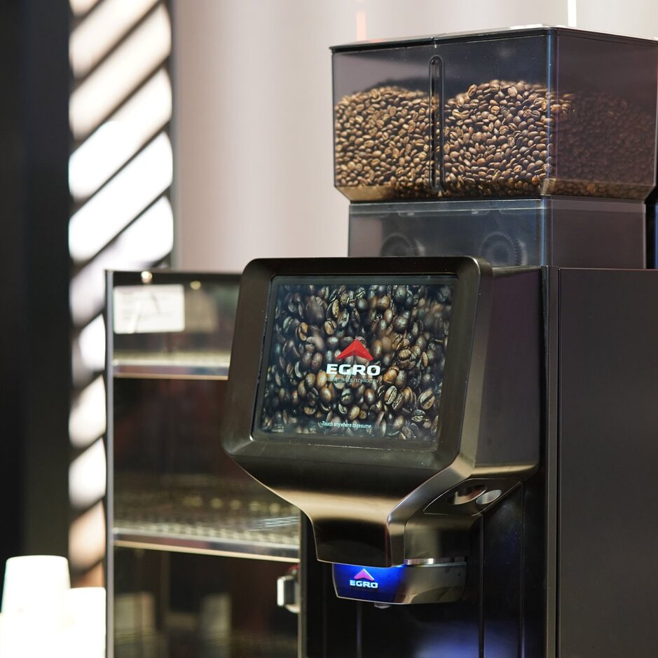 Egro NEXT Touch coffee machine featuring a touchscreen display and visible coffee beans in containers above.