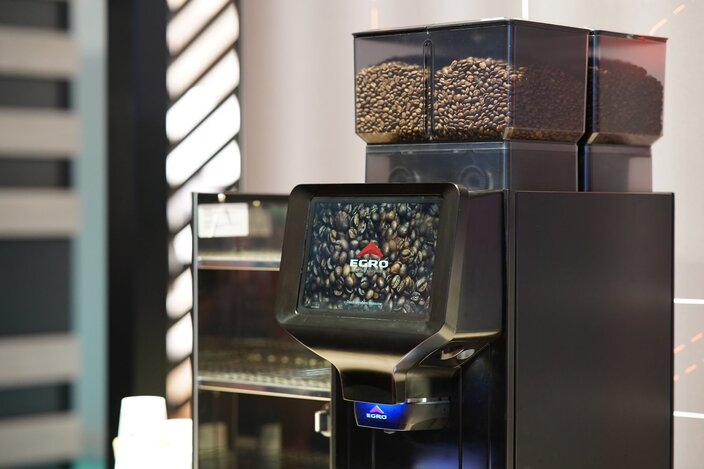 Egro NEXT Touch coffee machine featuring a touchscreen display and visible coffee beans in containers above.