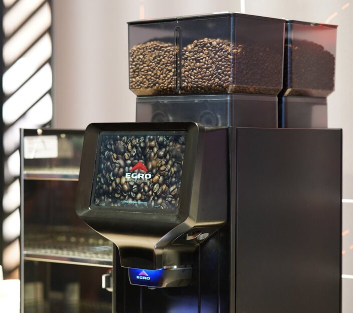 Egro NEXT Touch coffee machine featuring a touchscreen display and visible coffee beans in containers above.