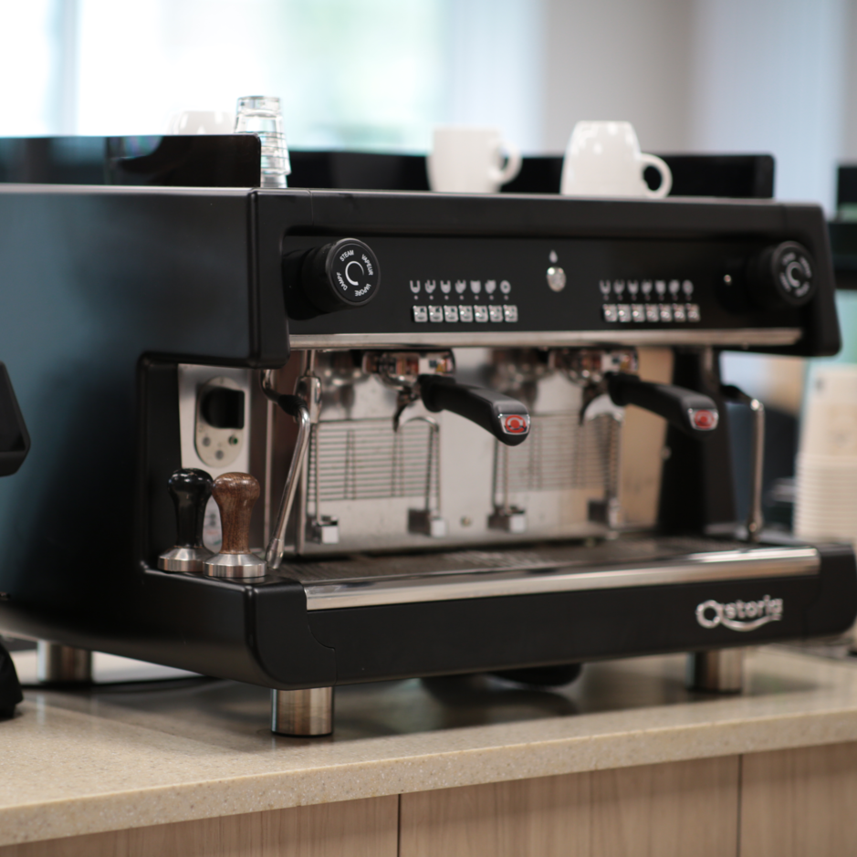 Sleek black espresso machine and grinder on a countertop, perfect for brewing high-quality coffee in a café setting.
