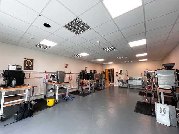 Spacious coffee roasting workshop featuring equipment, workstations, and tools for brewing and coffee preparation.