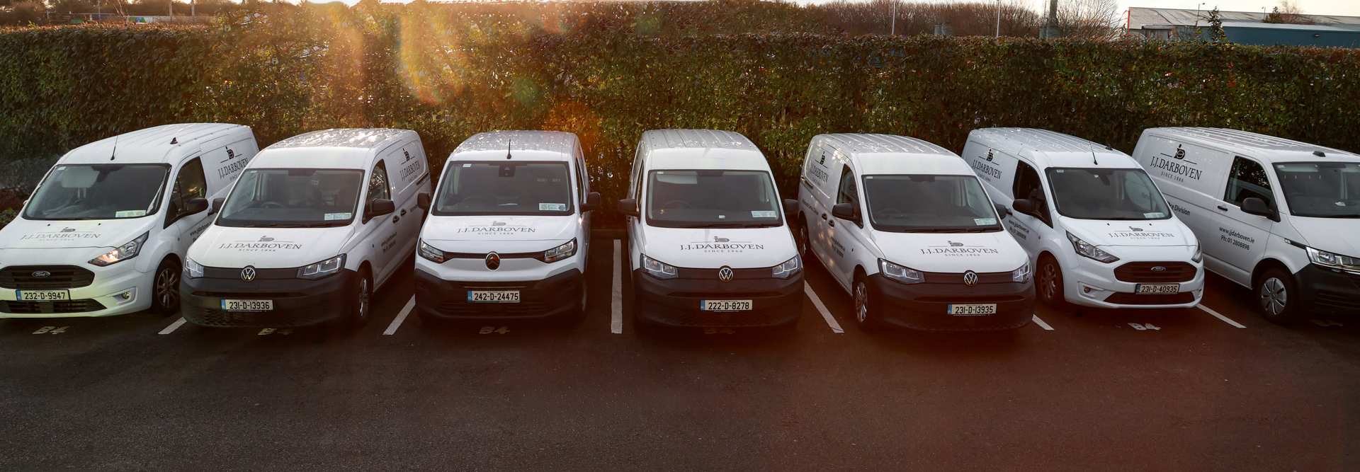 Fleet of parked delivery vans displaying the JJ Darboven logo in a commercial parking area.