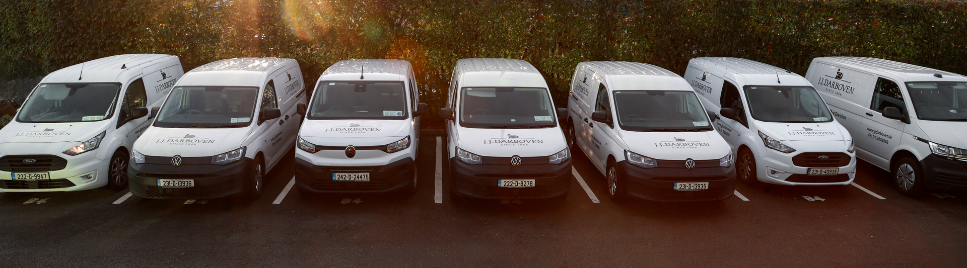 Fleet of parked delivery vans displaying the JJ Darboven logo in a commercial parking area.