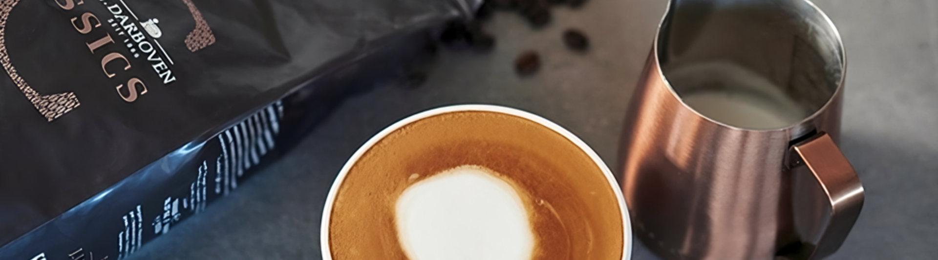 L'art du latte crémeux se trouve à côté de grains de café et d'un pot à lait, parfait pour les amateurs de café et les passionnés de cafés.