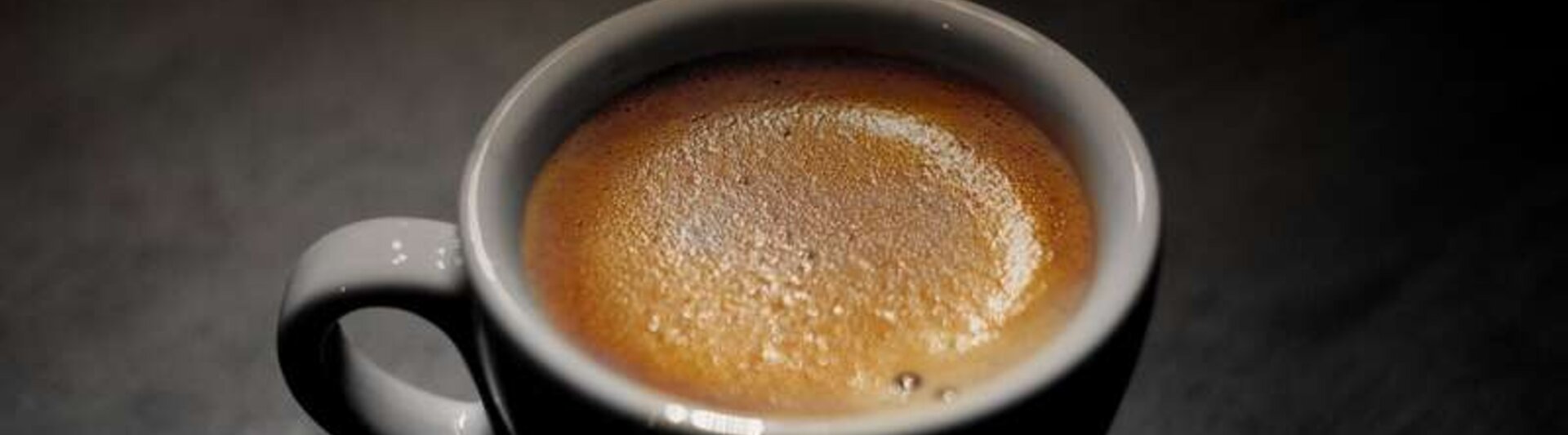 Un espresso riche dans une tasse blanche à la surface mousseuse, idéale pour les amateurs de café et pour inspirer la décoration d'un café.