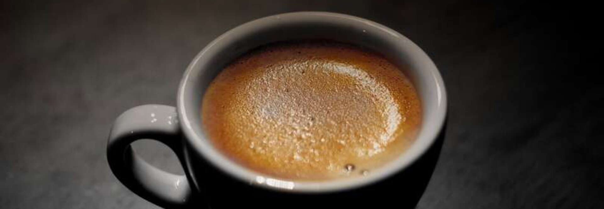Un espresso riche dans une tasse blanche à la surface mousseuse, idéale pour les amateurs de café et pour inspirer la décoration d'un café.