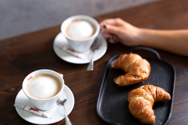 Café et croissants sur une table en bois, parfaits pour un petit-déjeuner ou un brunch tranquille dans un cadre de café.
