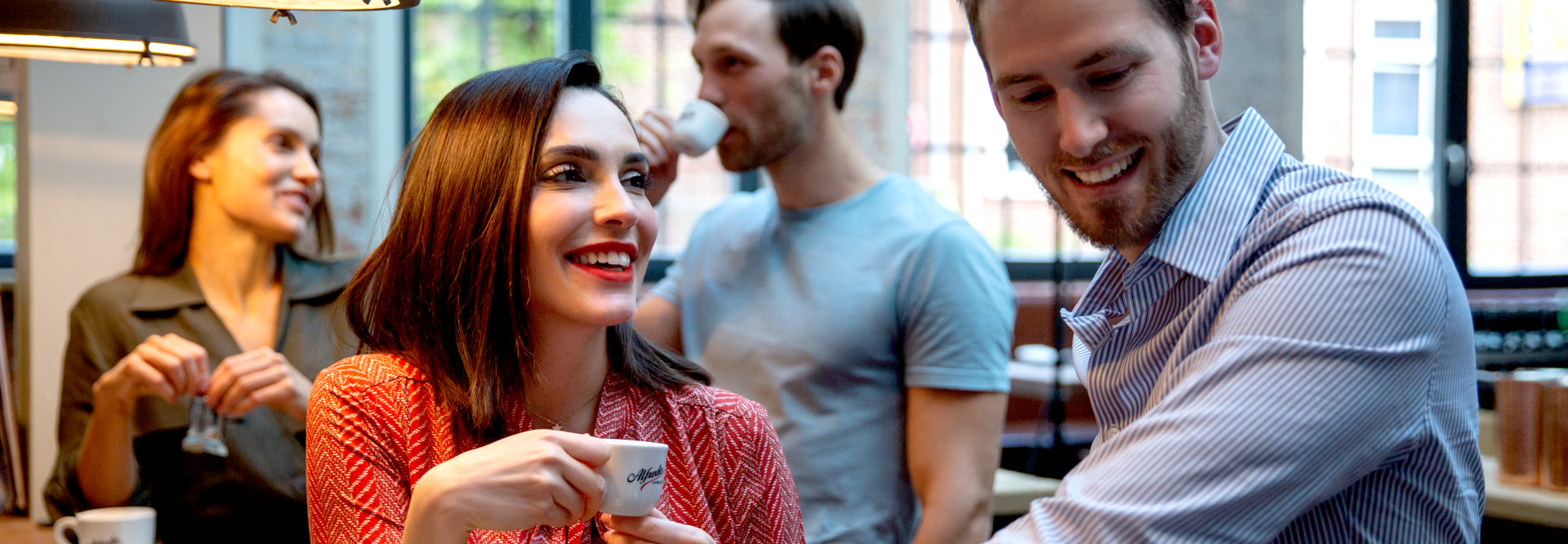 Vrienden genieten van koffie in een trendy café, lachen en kletsen rond een houten tafel in een levendige sociale omgeving.