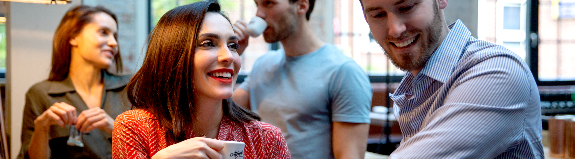 Vrienden genieten van koffie in een trendy café, lachen en kletsen rond een houten tafel in een levendige sociale omgeving.