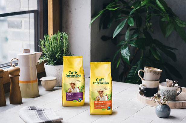 Café Intención tassen, Fuerte en Aromático, naast koffiekopjes op een keukentafel, die een stijlvolle café-setting laten zien.