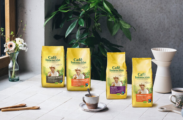 Café Intención-koffiezakken uitgestald op een tafel met een kopje, met Fair Trade-opties voor koffieliefhebbers.