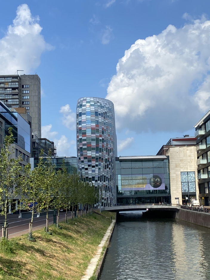 Modern Crown Plaza hotel in Utrecht, weerspiegeld aan de gracht, omgeven door hedendaagse architectuur en groen.