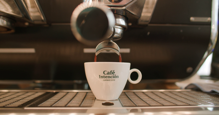 Vers gezette koffie stroomt in een witte mok uit een professionele espressomachine in Café Intención.