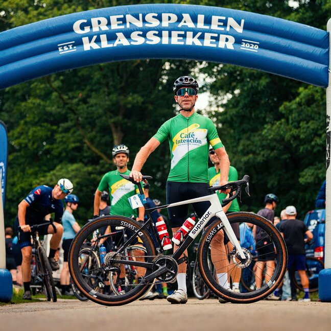 Fietser op het evenement Grenspalen Klassieker, klaar om te racen onder de opblaasbare boog in Brabant, 2024.