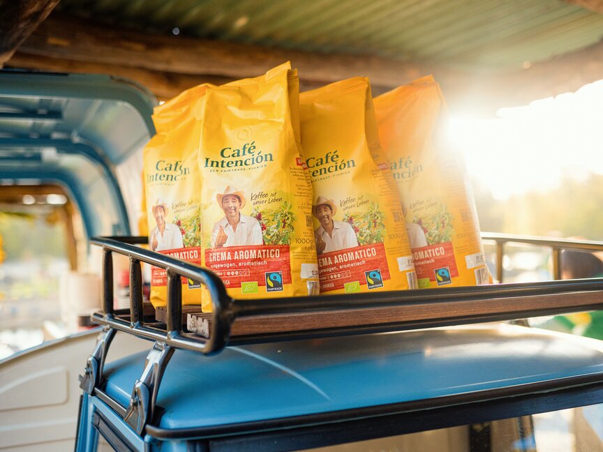 Fairtrade zakken Café Intención-koffie op de imperiaal van een auto, verlicht door warm zonlicht. Perfect voor koffieliefhebbers.