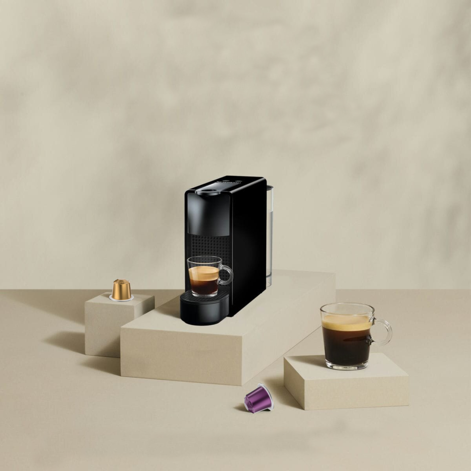Strakke koffiemachine met glazen espresso en kleurrijke koffiecapsules voor een stijlvolle keukensetting.