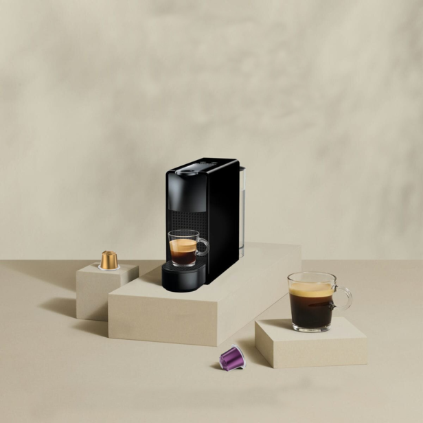 Strakke koffiemachine met glazen espresso en kleurrijke koffiecapsules voor een stijlvolle keukensetting.