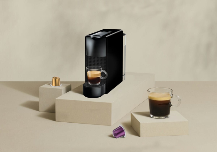 Strakke koffiemachine met glazen espresso en kleurrijke koffiecapsules voor een stijlvolle keukensetting.