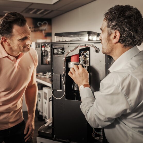 Teamleden van Braumann Brewer lossen een storing op bij een machine in een moderne kantooromgeving, waarbij ze blijk geven van samenwerking en vakkennis.