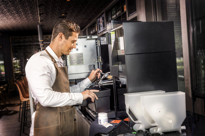Een barista die vakkundig koffie zet met een professionele koffiemachine in een modern café.