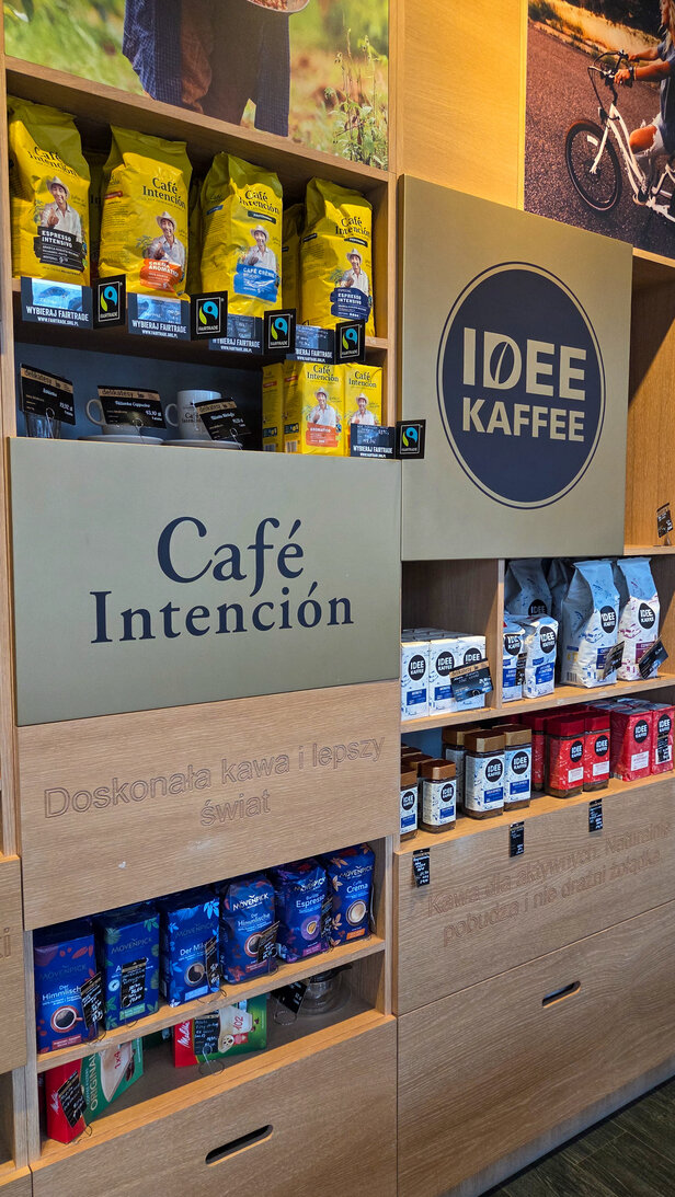 Wybór kaw Fairtrade w Café Intención, prezentujący różne mieszanki w żywych opakowaniach i drewnianych ekspozytorach.