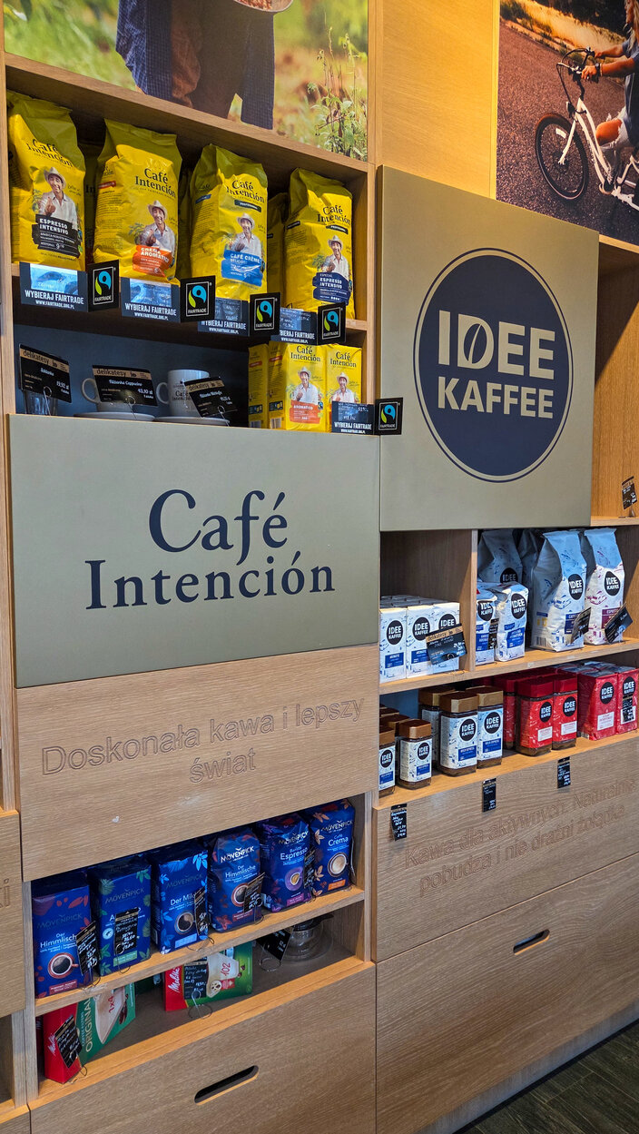Wybór kaw Fairtrade w Café Intención, prezentujący różne mieszanki w żywych opakowaniach i drewnianych ekspozytorach.