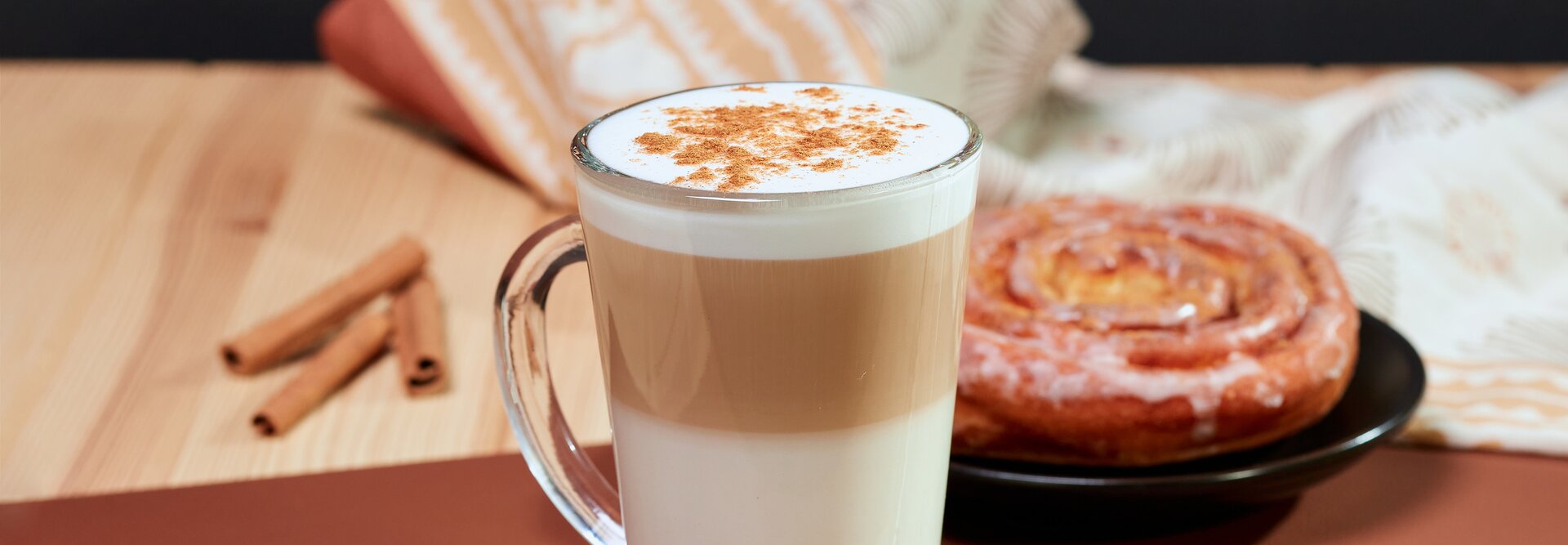 Rozkoszuj się warstwową kawą z cynamonem, połączoną ze świeżo upieczoną bułeczką cynamonową, aby uzyskać przytulny jesienny smakołyk.