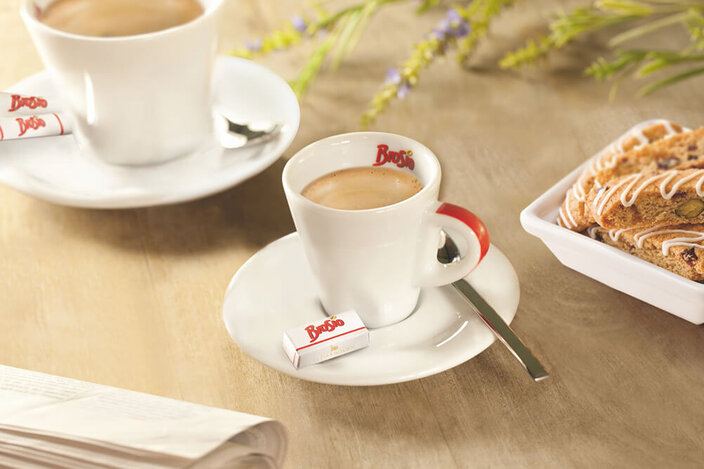 Déguster un café Brosio accompagné d'une friandise, avec des biscotti et une tasse élégante sur une table rustique.