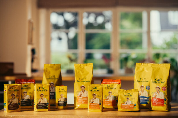 Café Intención coffee bags arranged on a wooden table, showcasing various blends and flavours in a bright café setting.