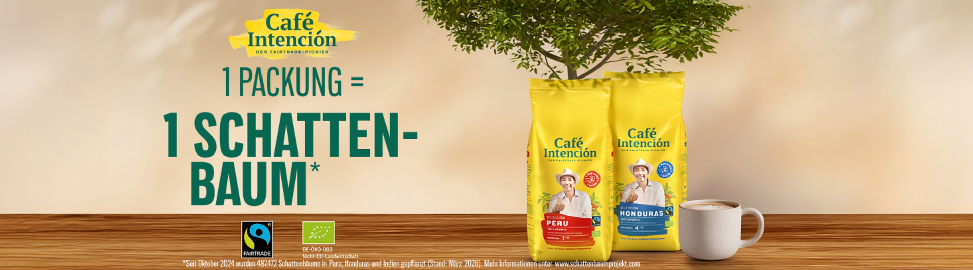 Verpackung von „Café Intención“ mit Fairtrade-Kaffee aus Peru und Honduras vor dem Hintergrund einer Kaffeetasse und einer Pflanze.