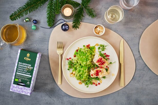 Köstliches grünes Erbsenrisotto mit Kabeljau, garniert mit Granatapfel und grünem Bio-Tee, für ein festliches Essen.