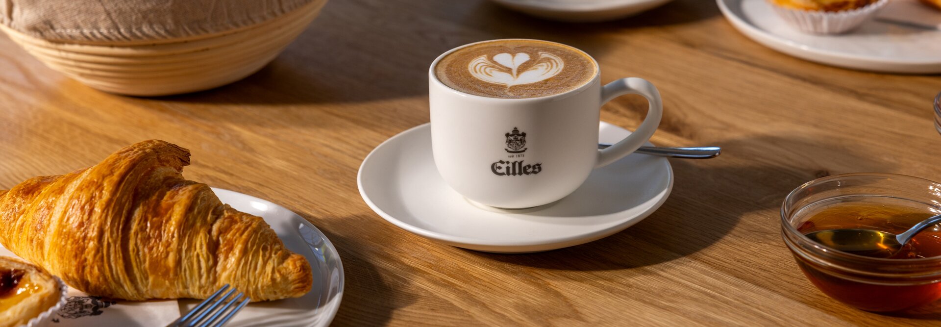 Vynikajúce croissanty a káva latte art podávané na drevenom stole, ktoré sú ideálne pre pôvabný kaviarenský zážitok.