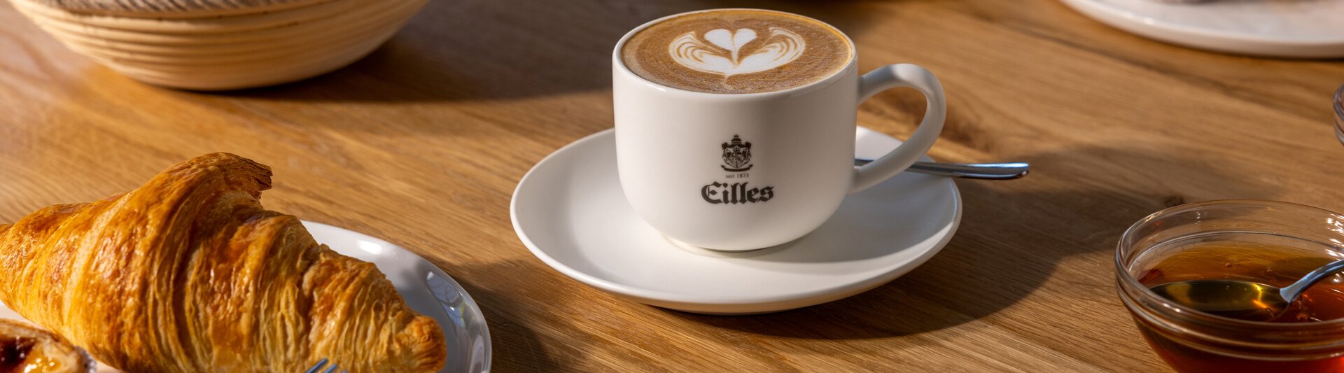 Vynikajúce croissanty a káva latte art podávané na drevenom stole, ktoré sú ideálne pre pôvabný kaviarenský zážitok.