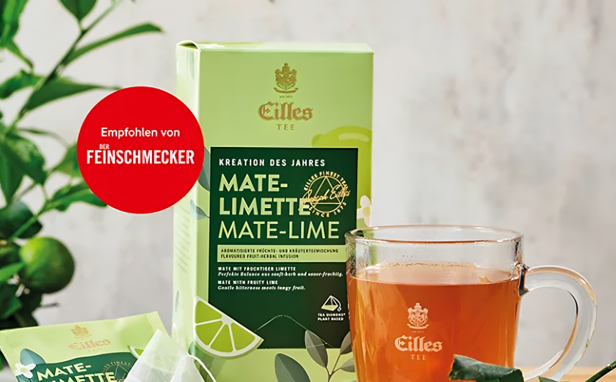 Erfrischender Eilles-Tee in der Geschmacksrichtung Mate-Limette, präsentiert mit einer Verpackung, einem Glas und natürlichem Grün für ein einladendes Ambiente.