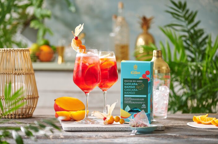 Refreshing Eilles Cascara Mango tea served in glasses, garnished with mango slices and vibrant fruits. Perfect summer drink!
