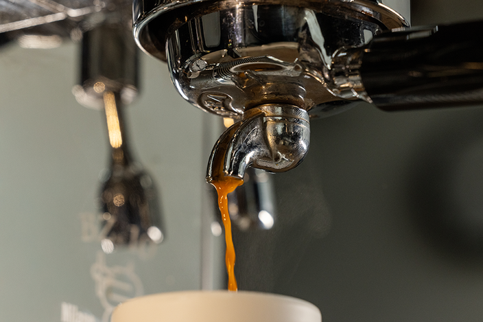 Verse espresso stroomt uit een chromen koffiemachine-uitloop en creëert stoom in een stijlvolle keukenomgeving.