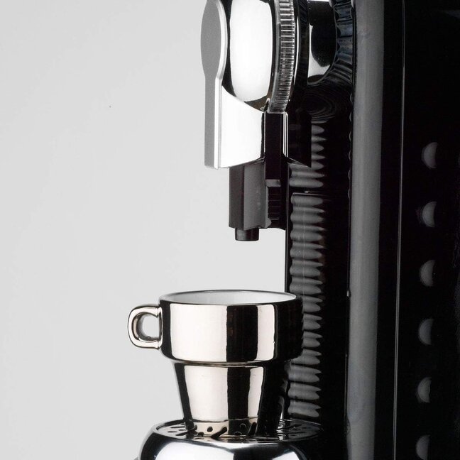 Machine à café à capsules compacte au design épuré, prête à préparer un expresso frais dans une tasse métallique.